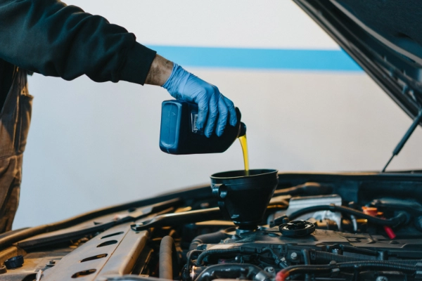 Mecânico utilizando funil para adicionar óleo lubrificante novo no motor do veículo